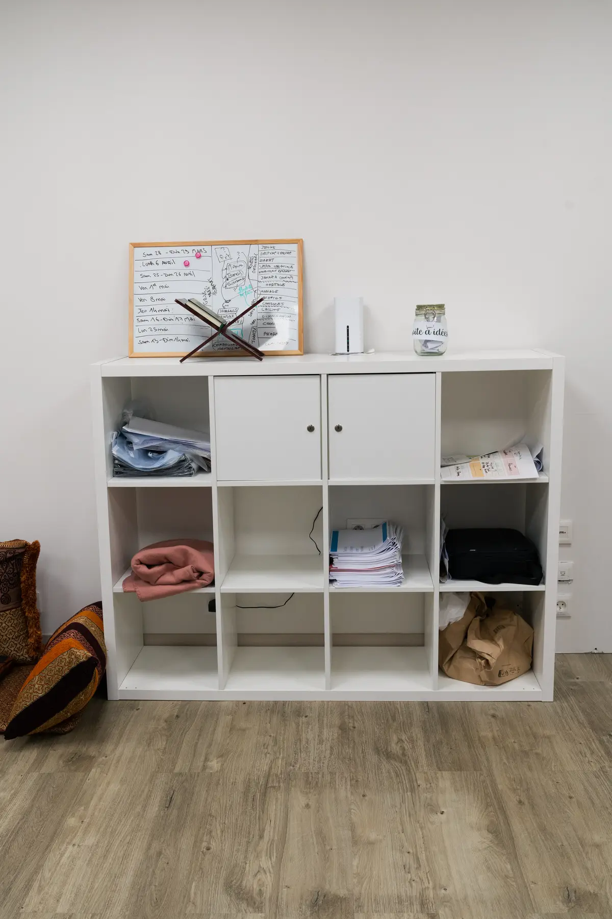 Le rangement de l’entrée : les casiers ouverts, les couvertures pliées, le tableau de planning posé dessus et les chaussures au sol.