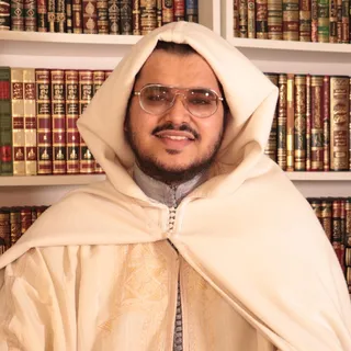 Chaykh Ismaïl ar-Rubaysī devant une bibliothèque.